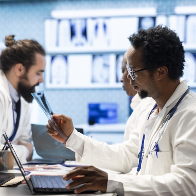 Diverse doctors team in a meeting discussing treatment services in cabinet. Licensed doctors reviewing x ray results and hospital records to develop effective treatment plans, expertise.